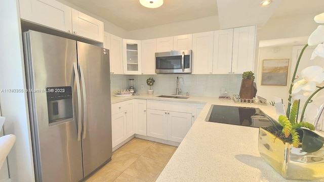 kitchen featuring white cabinets, decorative backsplash, glass insert cabinets, stainless steel appliances, and a sink