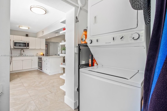 laundry area featuring stacked washer and dryer, light tile patterned floors, laundry area, and a sink