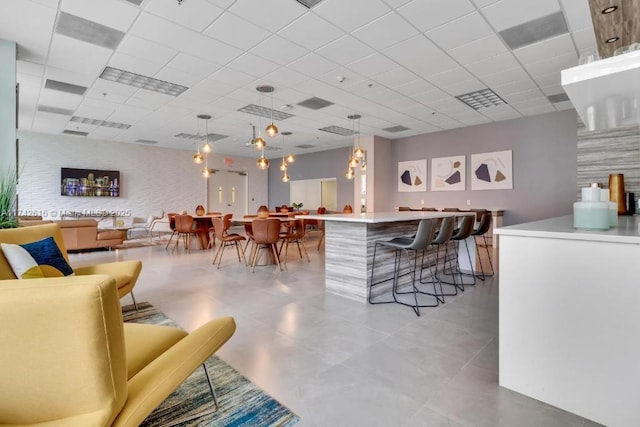 interior space with a kitchen island, a drop ceiling, a kitchen breakfast bar, and decorative light fixtures