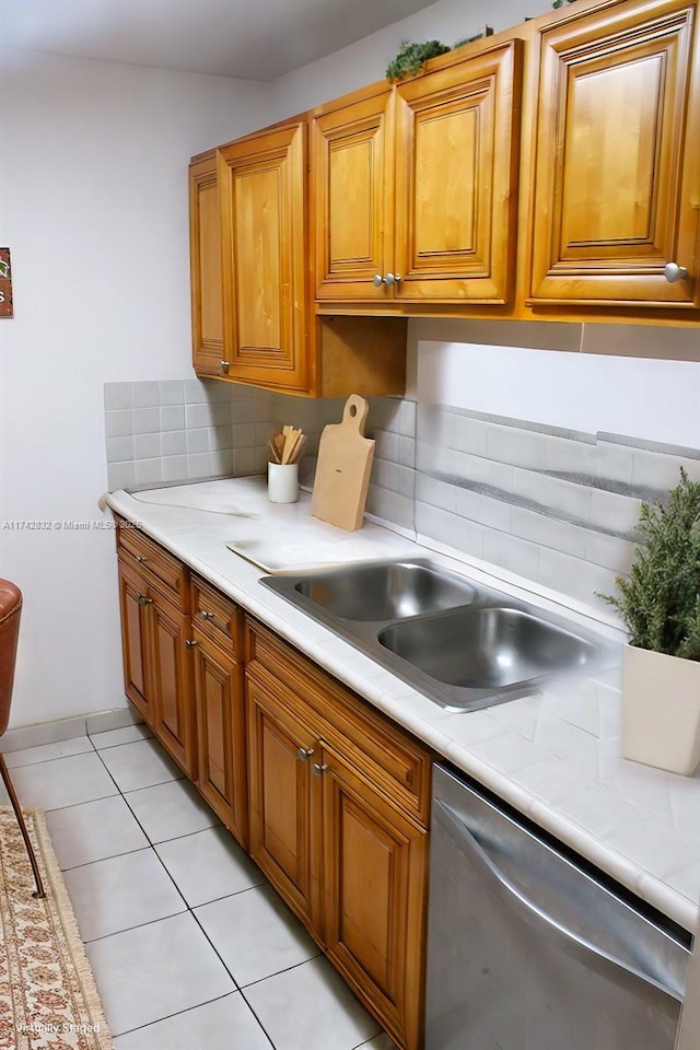 kitchen featuring light tile patterned flooring, dishwasher, sink, and tasteful backsplash