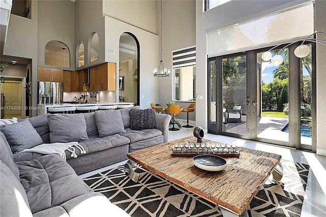 living room with french doors, a chandelier, and a high ceiling