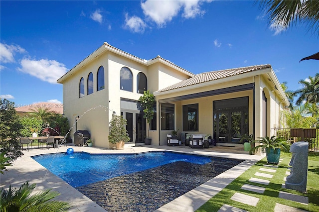 rear view of property with a fenced in pool, pool water feature, a patio area, and french doors