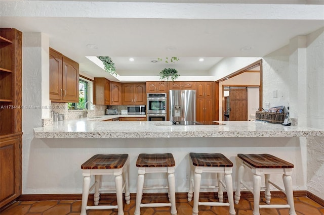 kitchen featuring appliances with stainless steel finishes, sink, a breakfast bar area, and kitchen peninsula