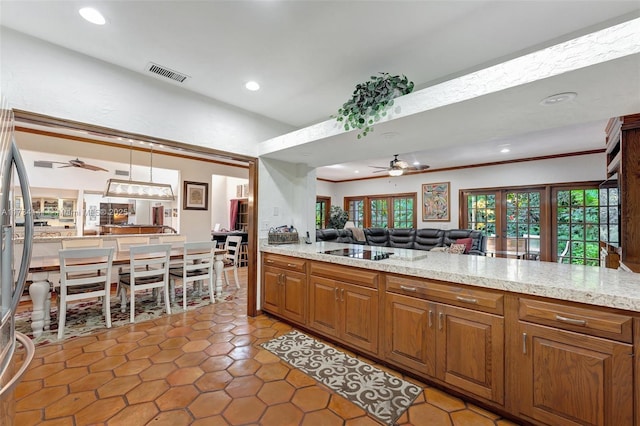 kitchen featuring hanging light fixtures, ceiling fan, crown molding, light stone countertops, and black electric cooktop