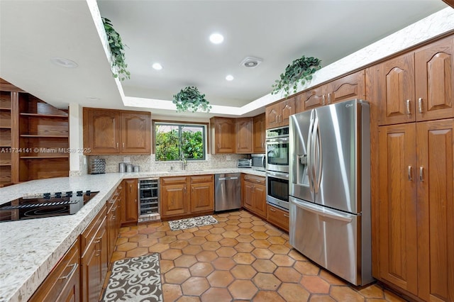 kitchen with sink, appliances with stainless steel finishes, wine cooler, tasteful backsplash, and a tray ceiling