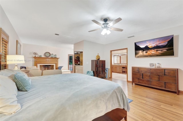 bedroom featuring ceiling fan, ensuite bathroom, and light wood-type flooring