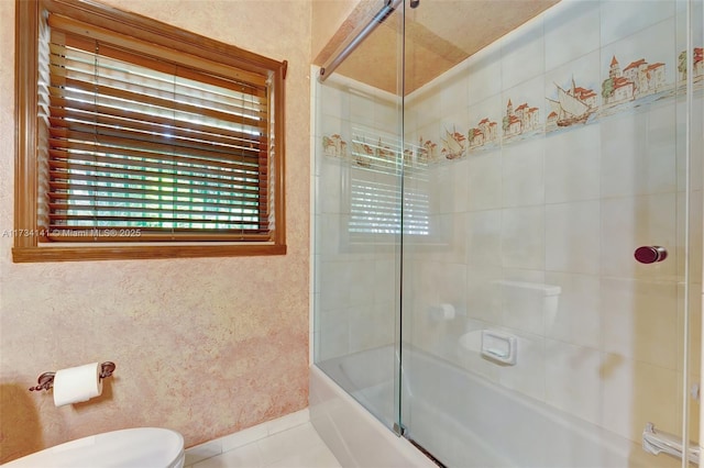 bathroom featuring bath / shower combo with glass door, tile patterned floors, and toilet