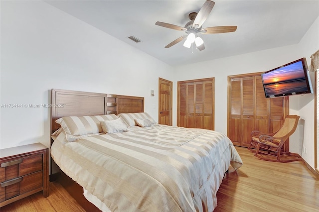 bedroom with multiple closets, ceiling fan, and light hardwood / wood-style flooring