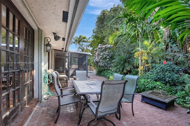 view of patio / terrace featuring an outdoor fire pit and a sunroom