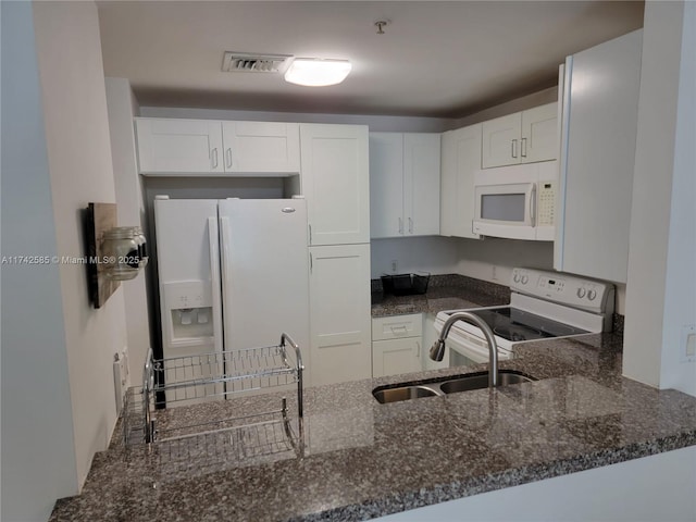 kitchen featuring sink, white cabinets, dark stone counters, kitchen peninsula, and white appliances