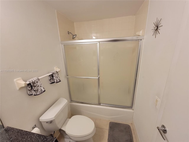 bathroom featuring tile patterned flooring, bath / shower combo with glass door, and toilet