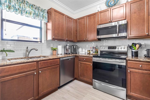 kitchen with sink, appliances with stainless steel finishes, light stone counters, ornamental molding, and decorative backsplash