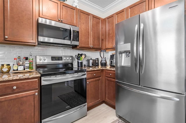 kitchen with light stone countertops, appliances with stainless steel finishes, ornamental molding, and decorative backsplash