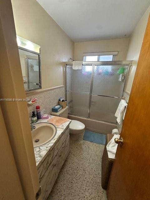 full bathroom featuring vanity, combined bath / shower with glass door, tile walls, and toilet