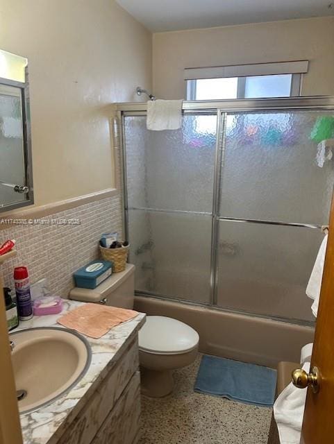 full bathroom featuring vanity, tile walls, shower / bath combination with glass door, and toilet