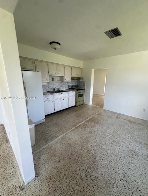 kitchen with decorative backsplash, range, sink, and white fridge