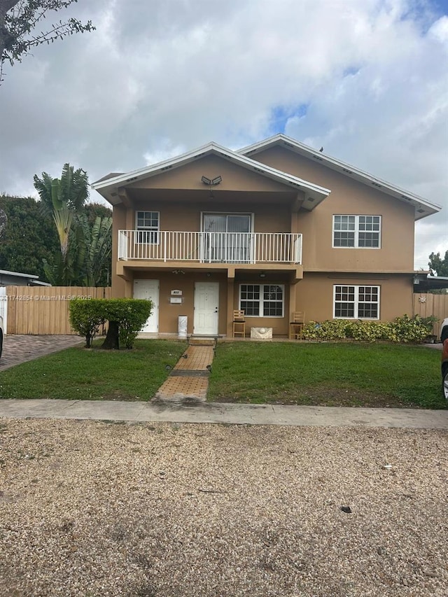 view of property featuring a balcony and a front yard