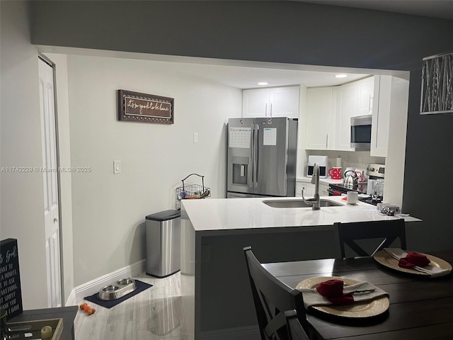 kitchen featuring white cabinetry, appliances with stainless steel finishes, kitchen peninsula, and sink