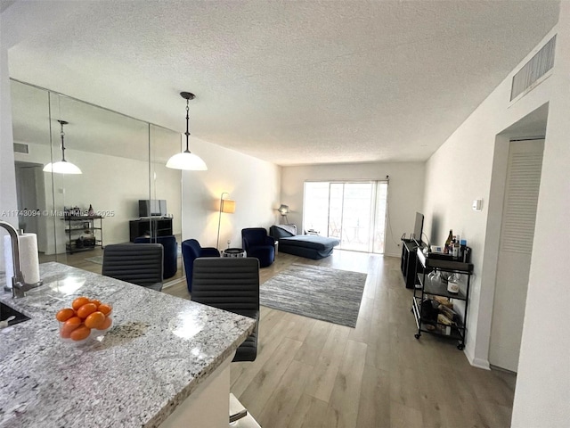 5102 NW 36th St Unit 611, Lauderdale Lakes, FL 33319 - living area featuring light wood-style flooring, a textured ceiling, and baseboards