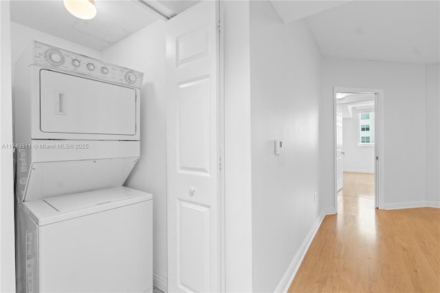 clothes washing area featuring stacked washer / drying machine and light hardwood / wood-style floors