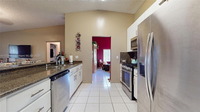 kitchen featuring vaulted ceiling, white cabinetry, sink, light tile patterned floors, and stainless steel appliances