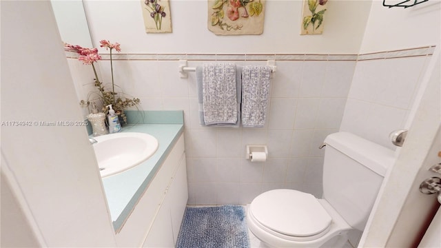 bathroom featuring vanity, toilet, and tile walls