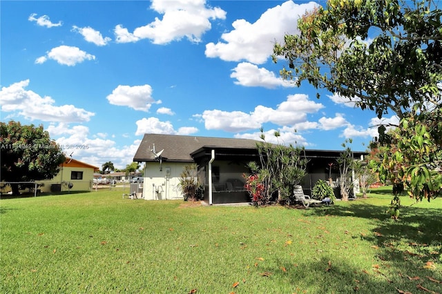 rear view of house with a yard and a sunroom