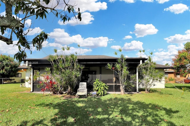 rear view of house with a yard and a sunroom