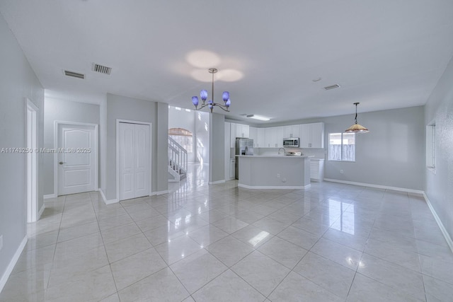 unfurnished living room with an inviting chandelier and light tile patterned floors