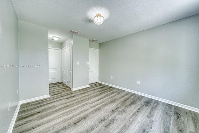 spare room with a textured ceiling and light wood-type flooring