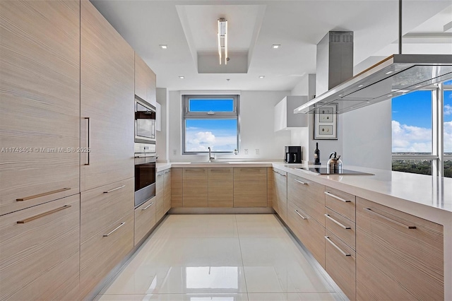 kitchen featuring sink, light tile patterned floors, island range hood, light brown cabinetry, and oven