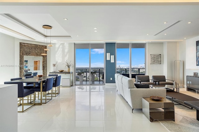 living room with a tray ceiling, a wealth of natural light, and a wall of windows