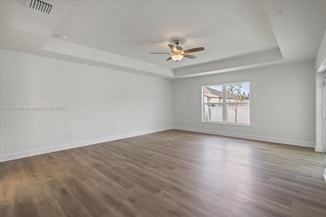 empty room with a tray ceiling and wood-type flooring