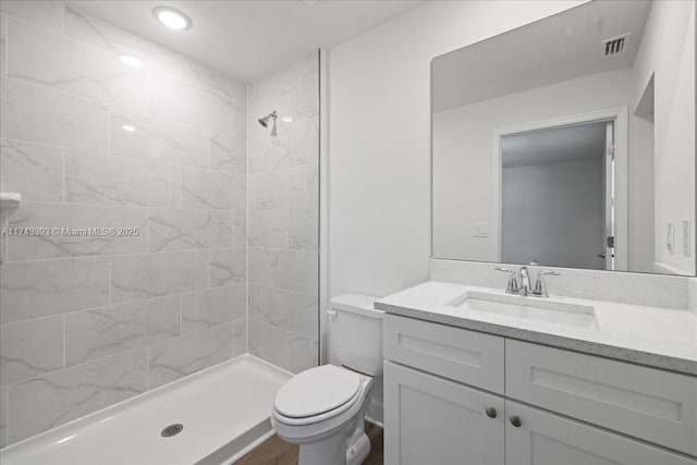 bathroom featuring vanity, toilet, and tiled shower