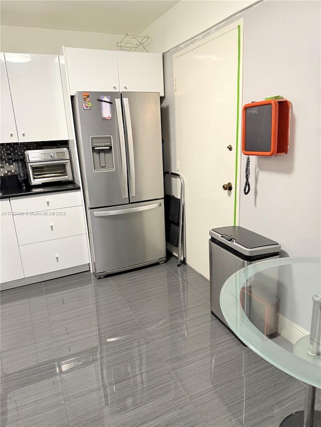 kitchen with white cabinetry, stainless steel fridge with ice dispenser, and dark tile patterned flooring