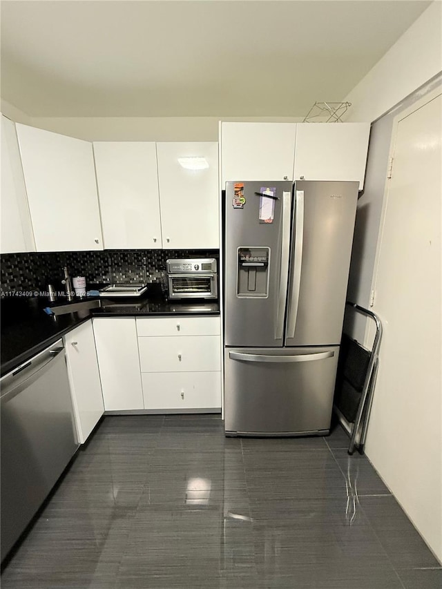 kitchen with appliances with stainless steel finishes, white cabinets, and backsplash