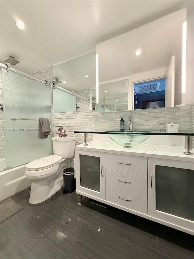 full bathroom featuring vanity, backsplash, shower / bath combination with glass door, and toilet