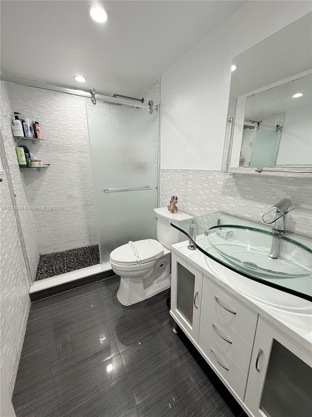 bathroom featuring tiled shower, vanity, toilet, and tile walls