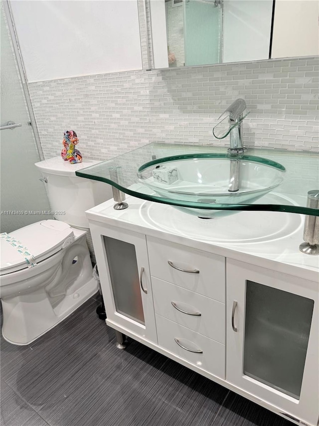 bathroom featuring vanity, backsplash, tile walls, and toilet