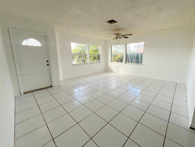 tiled foyer entrance with ceiling fan and a textured ceiling