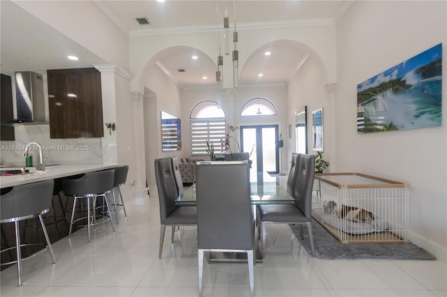 dining space with decorative columns, crown molding, and sink