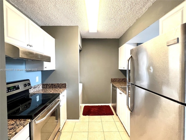 kitchen featuring white cabinetry, stainless steel appliances, light tile patterned floors, and dark stone countertops