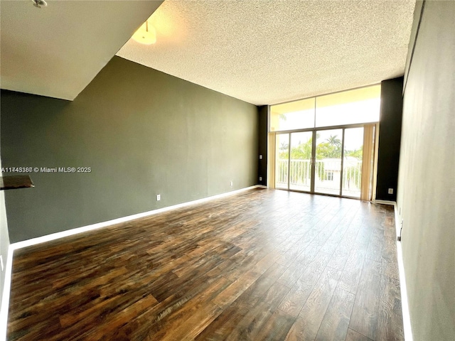 unfurnished room with wood-type flooring, floor to ceiling windows, and a textured ceiling