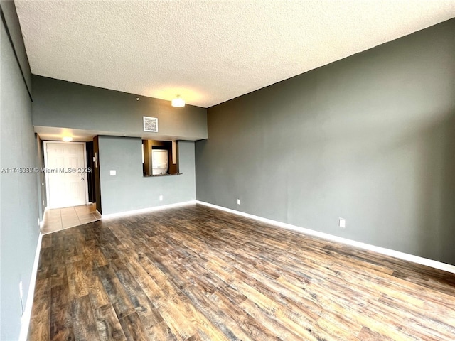 empty room with hardwood / wood-style floors and a textured ceiling