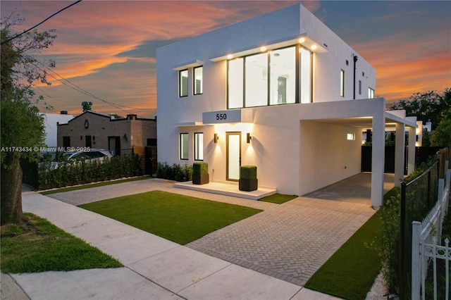 contemporary home featuring a carport and a lawn