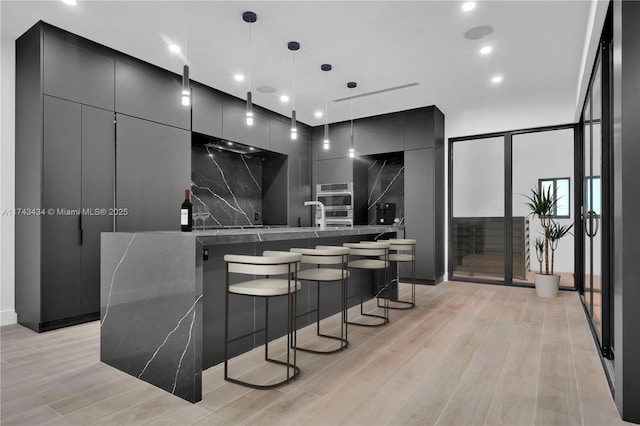 interior space with tasteful backsplash, a spacious island, a breakfast bar area, and decorative light fixtures