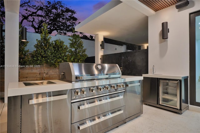 patio terrace at dusk featuring area for grilling, wine cooler, and an outdoor kitchen