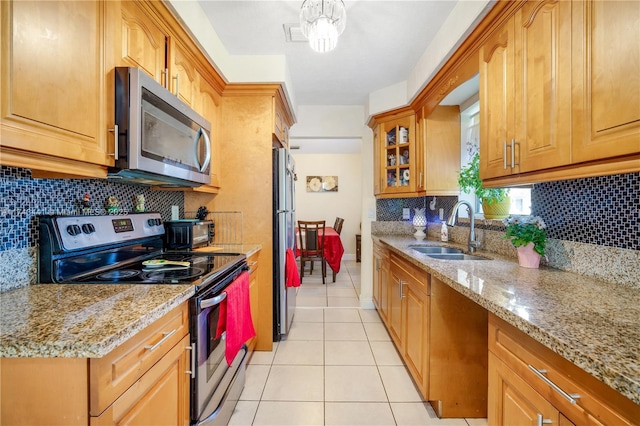 kitchen featuring sink, light tile patterned floors, appliances with stainless steel finishes, light stone countertops, and backsplash