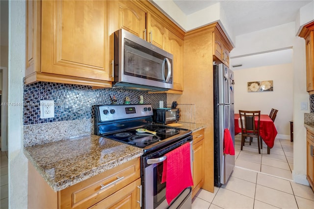 kitchen with light tile patterned floors, decorative backsplash, light stone countertops, and appliances with stainless steel finishes