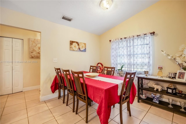 tiled dining space featuring vaulted ceiling